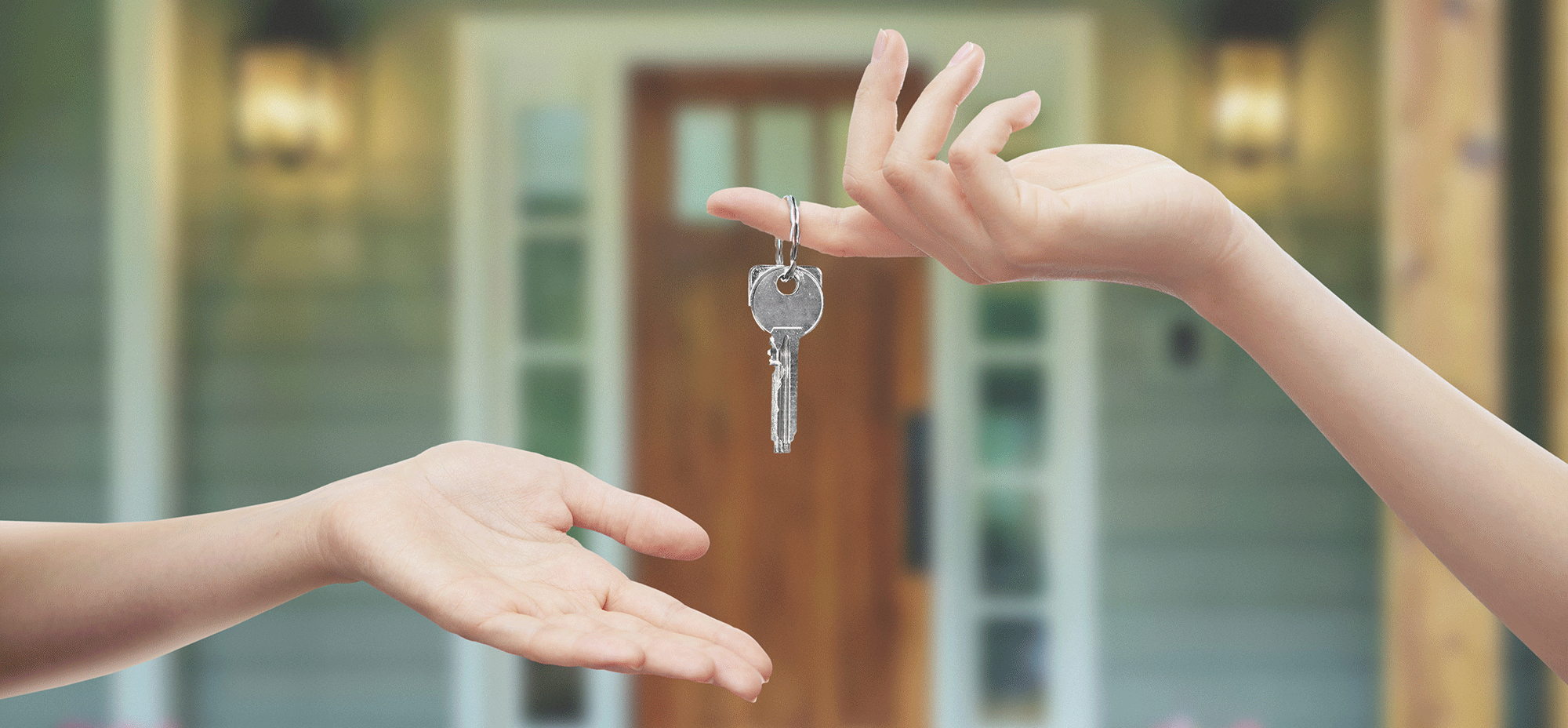 Two hands exchanging keys to a new home.